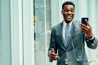 Positive young businessman using smartphone outside wearing suit and tie