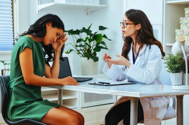 young female doctor explaining treatment to worried woman patient at health checkup