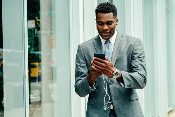 Positive young entrepreneur using smartphone outside wearing suit and tie hand in thumbs up
