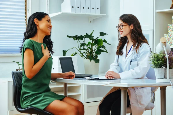 smiling female patient explaining illness to happy woman doctor consultation clinic health checkup