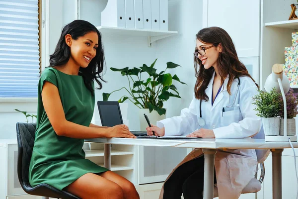 young female doctor smiling with woman patient consultation clinic health checkup taking notes