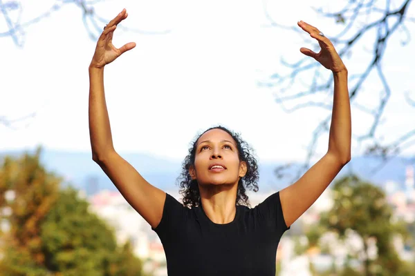 woman outdoors, arms raised curly hair sportswear