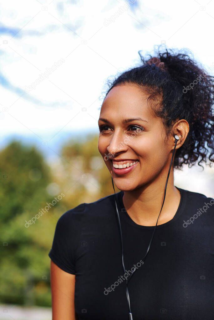 close up woman outdoors with earphones smiling looking away