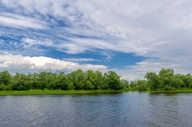 summer photo on a large deep river, powerful storm clouds, blue sky, dark harsh water, tourist walk along the Kama river