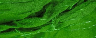 Yeşil ipek kumaş ve lurex. Parlak doku arka plan, saten arka plan, lüks kumaş, zarif desen, renkli soyut, renkli kadife, parçalanmış makro.