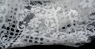 dantel kumaş. Kuş tüyü. Siyah arka planda beyaz. Dantel moda ve ev dekorasyonuna hükmediyor. Tasarımlarınızı, kartpostallarınızı, döşemelerinizi ve daha fazlasını dikkatle vurguluyor..