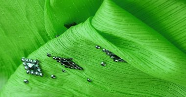 Yapışkan dekoratif taşlı yeşil kumaş. parlak renkli taşlarla dokuma arkaplanı, arkaplan dokusu tasarımı. İpek deseni,