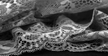 Siyah dantel. Klasik çiçek arkaplanı. Dantelli kumaş, taban tarafından birbirine bağlanmış motifler oluşturan iplikleri çaprazlayarak elde edilen bir açılış kumaşıdır.