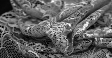 Siyah dantel. Klasik çiçek arkaplanı. Dantelli kumaş, taban tarafından birbirine bağlanmış motifler oluşturan iplikleri çaprazlayarak elde edilen bir açılış kumaşıdır.