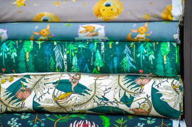 Kumaş koleksiyonu tezgahta. Mağazadaki raflarda farklı renk ve desenlerde kumaş rulolarının görüntüsü. Doku. Geçmişi. Şablon