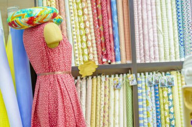 Kumaş koleksiyonu tezgahta. Mağazadaki raflarda farklı renk ve desenlerde kumaş rulolarının görüntüsü. Doku. Geçmişi. Şablon