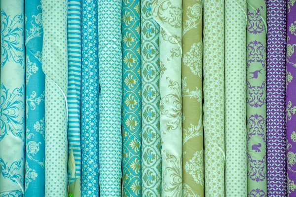 Collection of fabrics at the store counter. View of rolls of fabric in different colors and patterns on the shelves in the store. Texture. background. Template