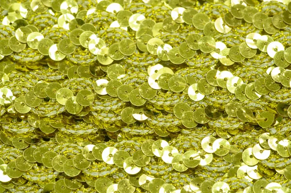 Pale green sequins. Ribbon for fabric decoration. Background texture, sunrise. Smooth slope of rows of round pale green sequins on a fine fabric mesh.