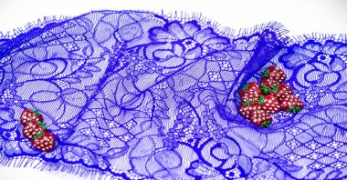 Mavi dantelli kumaş. Plastik çilekler. Dekoratif çilekler kumaşa dikilebilir. Parlak dekorasyon. Desen Arkaplan Deseni