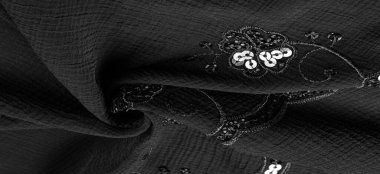 İpek siyahı. Kumaş pullarla süslenmiş. arka plan, ipek saten, lüks kumaş, koyu kumaş, kostüm pamuğu, soyut renk kalıbı, hassas sıvı kömür kadife.