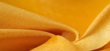 Sarı renkli ipek kumaş. Renkli ipek kumaşın dokusu arka plan olarak kullanılabilir