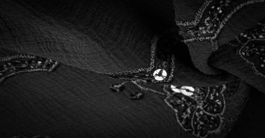 İpek siyahı. Kumaş pullarla süslenmiş. arka plan, ipek saten, lüks kumaş, koyu kumaş, kostüm pamuğu, soyut renk kalıbı, hassas sıvı kömür kadife.