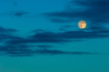 Gece fotoğrafı. Gökyüzündeki bulutlu ay güneş tarafından renklendirilir. Ay ışığı, ay ışığı, ışık