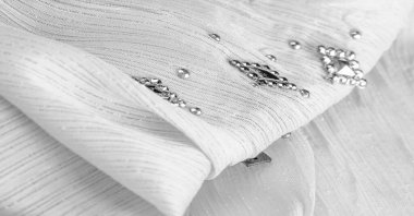 Süslü, süslemeli taşlı beyaz kumaş. parlak renkli taşlarla dokuma arkaplanı, doku arkaplan tasarımı. İpek deseni,