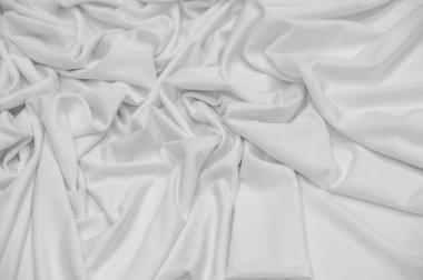 Beyaz ipek kumaş. Doku. Geçmişi. Şablon. Dupioni ipek kumaşının parlak bir parıltısı ve yatay hareket eden karakteristik küçük kıvrımları vardır. Yumuşak kıvrımlar içinde uzanır