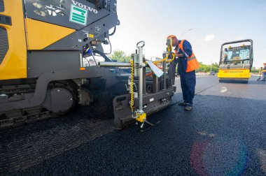 Yol yapımı. Bir inşaat sahasında, işçiler sıcak karışımı otoyola yayıp sıkıştırıyorlar. 1207 2021 Kzakhstan Orta Asya