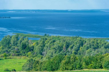 Yaz manzarası. Dünyanın Avrupa bölgesindeki bir nehir. Güneşli sıcak bir gün. Yeşil ağaçlar, çimenler. Mavi gökyüzü küçük bir bulut örtüsüyle.