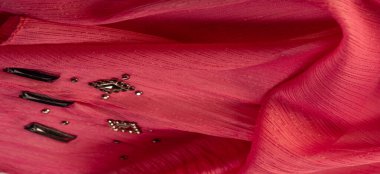 İpek desenli, kırmızı kumaş ve dekoratif yüzlü taşlar. parlak renkli taşlarla dokuma arkaplanı, doku arkaplan tasarımı