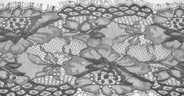 Black lace fabric on a white background. Fancy African tulle lace fabric polyester with full length flowers for your design. The texture. Background. Pattern