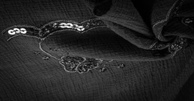 İpek siyahı. Kumaş pullarla süslenmiş. arka plan, ipek saten, lüks kumaş, koyu kumaş, kostüm pamuğu, soyut renk kalıbı, hassas sıvı kömür kadife.