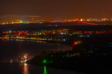 Büyük bir nehrin kıyısında gelişmiş bir petrokimya endüstrisi olan bir şehrin gece çekimi. Nizhnekamsk Kama. Parlak gece renkleri. Sonbahar dönemi