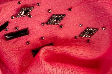 İpek desenli, kırmızı kumaş ve dekoratif yüzlü taşlar. parlak renkli taşlarla dokuma arkaplanı, doku arkaplan tasarımı