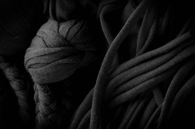 Fabric in black braids. Knitted knitted background with embossed pattern. Braids in knitting. Texture, background