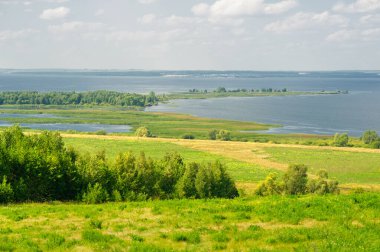 Yaz manzarası. Dünyanın Avrupa bölgesindeki bir nehir. Güneşli sıcak bir gün. Yeşil ağaçlar, çimenler. Mavi gökyüzü küçük bir bulut örtüsüyle.