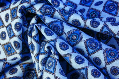 Yumuşak mavi ipekten kumaş eşkenar dörtgen, kare ve madalyalar. Bir hikaye anlat ve geleneksel tasarım ile etkileyici ve değerli bir açıklama yap. Desen arkaplan deseni