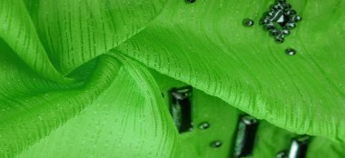 Yapışkan dekoratif taşlı yeşil kumaş. parlak renkli taşlarla dokuma arkaplanı, arkaplan dokusu tasarımı. İpek deseni,