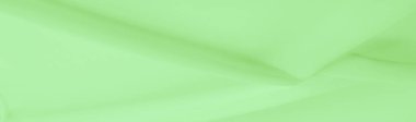 Açık yeşil ipek polyester. Kireç yeşili ipek kumaştan. Şeffaf arkaplan ve elbise dikmek için açık kumaştan yapılmış. Tekstil panoraması