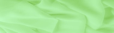 Açık yeşil ipek polyester. Kireç yeşili ipek kumaştan. Şeffaf arkaplan ve elbise dikmek için açık kumaştan yapılmış. Tekstil panoraması