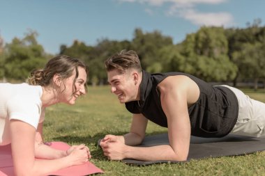 Two millennial friends practicing a pilates or yoga plank and laughing