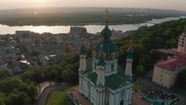 Vista aérea de la iglesia de St. Andrews al amanecer, centro histórico, distrito de Podolsk, Kiev, Ucrania. Un dron con una cámara vuela desde la Iglesia de San Andrés. Vuele alrededor de la iglesia de St. Andrews en Kiev. — Vídeos de Stock