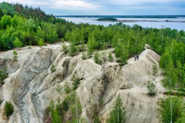 Colorful clay hills overgrown with green trees. Natural abstract landscape, aerial view, from drone