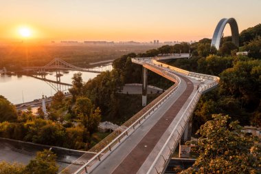 Kyiv 'de yaya bisiklet köprüsü, şafak vakti, güneşli hava, hava manzarası.
