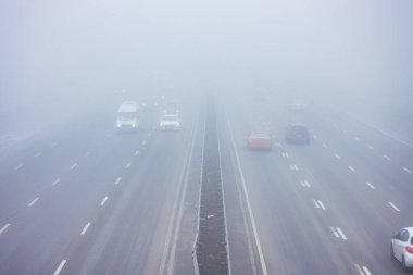 Siste arabalar var. Kötü kış havası ve yolda tehlikeli otomobil trafiği. Sisli günde hafif araçlar.