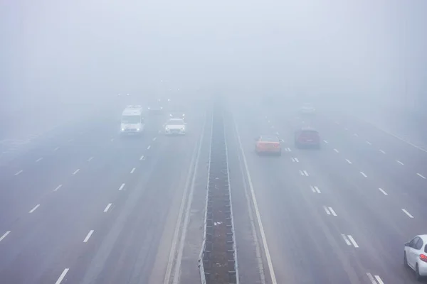 Cars in the fog. Bad winter weather, and dangerous automobile traffic on the road. Light vehicles in foggy day.