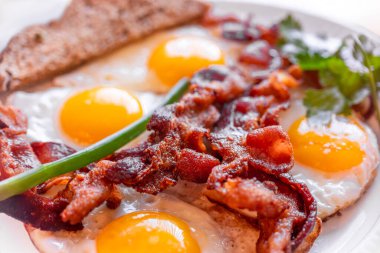 Lezzetli sahanda yumurta ve kıtır pastırma, yakın plan, harika klasik kahvaltı. Makro fotoğrafçılık, alanın sığ derinliği.
