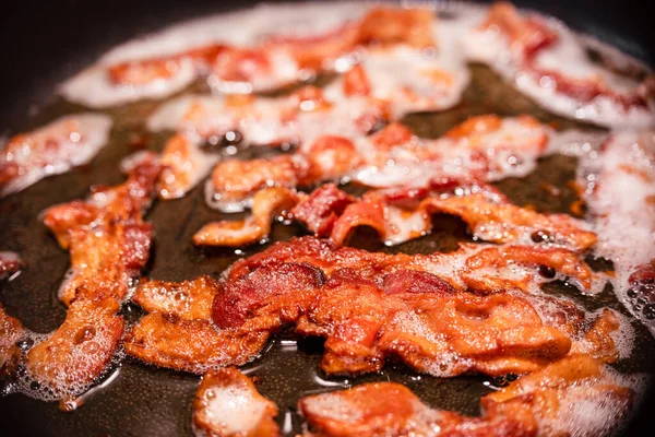 Macro view of appetizing, tasty, bacon slices in a frying pan, close-up, fried meat to scrambled eggs, shallow depth of field — Stockfoto