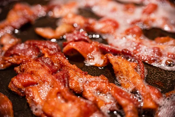 Macro view, of appetizing, tasty, bacon slices in a frying pan, close-up, fried meat to scrambled eggs, shallow depth of field