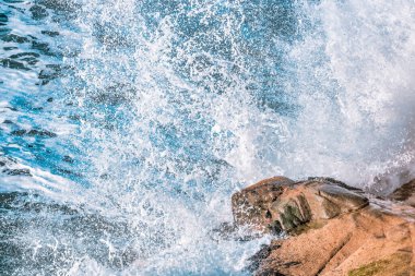 Pasifik Okyanusu 'nun güzel dalgaları kayalık kıyılara, yakın plan, pastel renklere vuruyor.