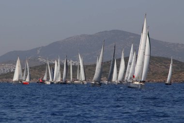 Bodrum, Türkiye. 14 Nisan 2018: Ünlü tatil beldesi Bodrum 'un kıyılarında, Ege Denizi' nin mavi sularında rüzgarlı havada yelken açan yelkenliler.
