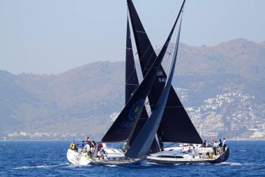 Bodrum, Türkiye. 14 Nisan 2018: Ünlü tatil beldesi Bodrum 'un kıyılarında, Ege Denizi' nin mavi sularında rüzgarlı havada yelken açan yelkenliler.