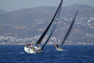 Bodrum, Türkiye. 14 Nisan 2018: Ünlü tatil beldesi Bodrum 'un kıyılarında, Ege Denizi' nin mavi sularında rüzgarlı havada yelken açan yelkenliler.